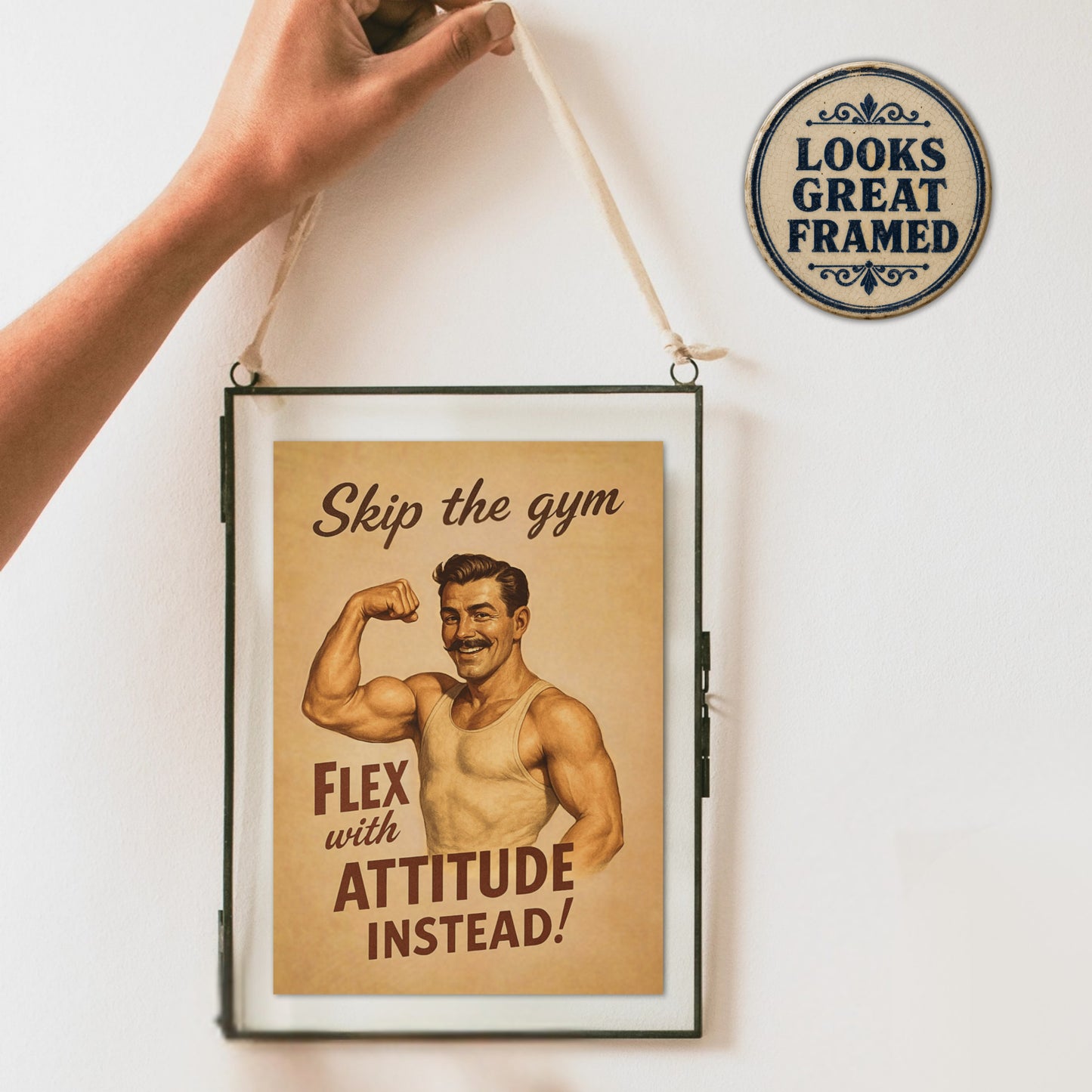 Framed poster card with a vintage-style illustration of a muscular man and text, held up against a white wall.