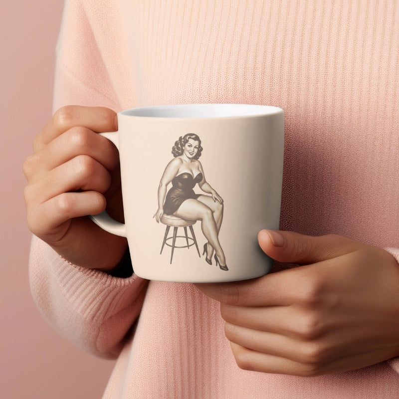 Person holding a mug with a vintage-style illustration of a woman on a stool against a pink background