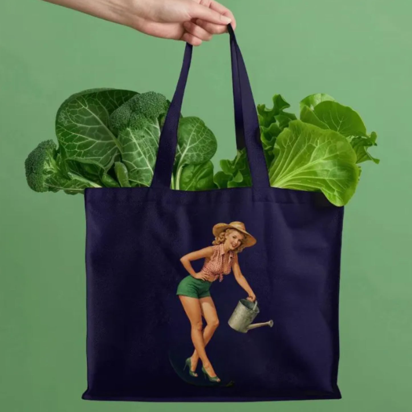 Navy tote bag with a garden-themed design filled with green vegetables on a green background