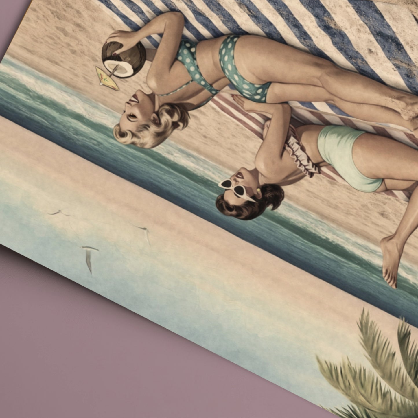 Two women in vintage swimwear lying on a striped towel with a beach scene.