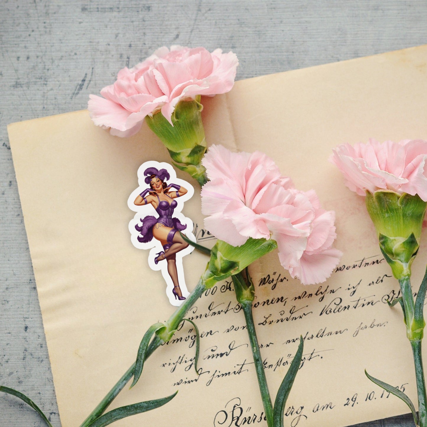 Pink carnations on an old letter with a sticker of a burlesque woman in a purple dress.