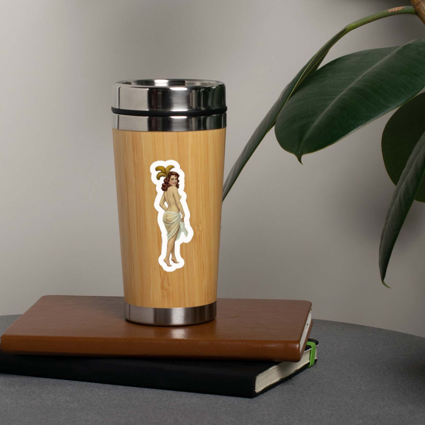 Wooden travel mug with a metal lid on a book next to a plant