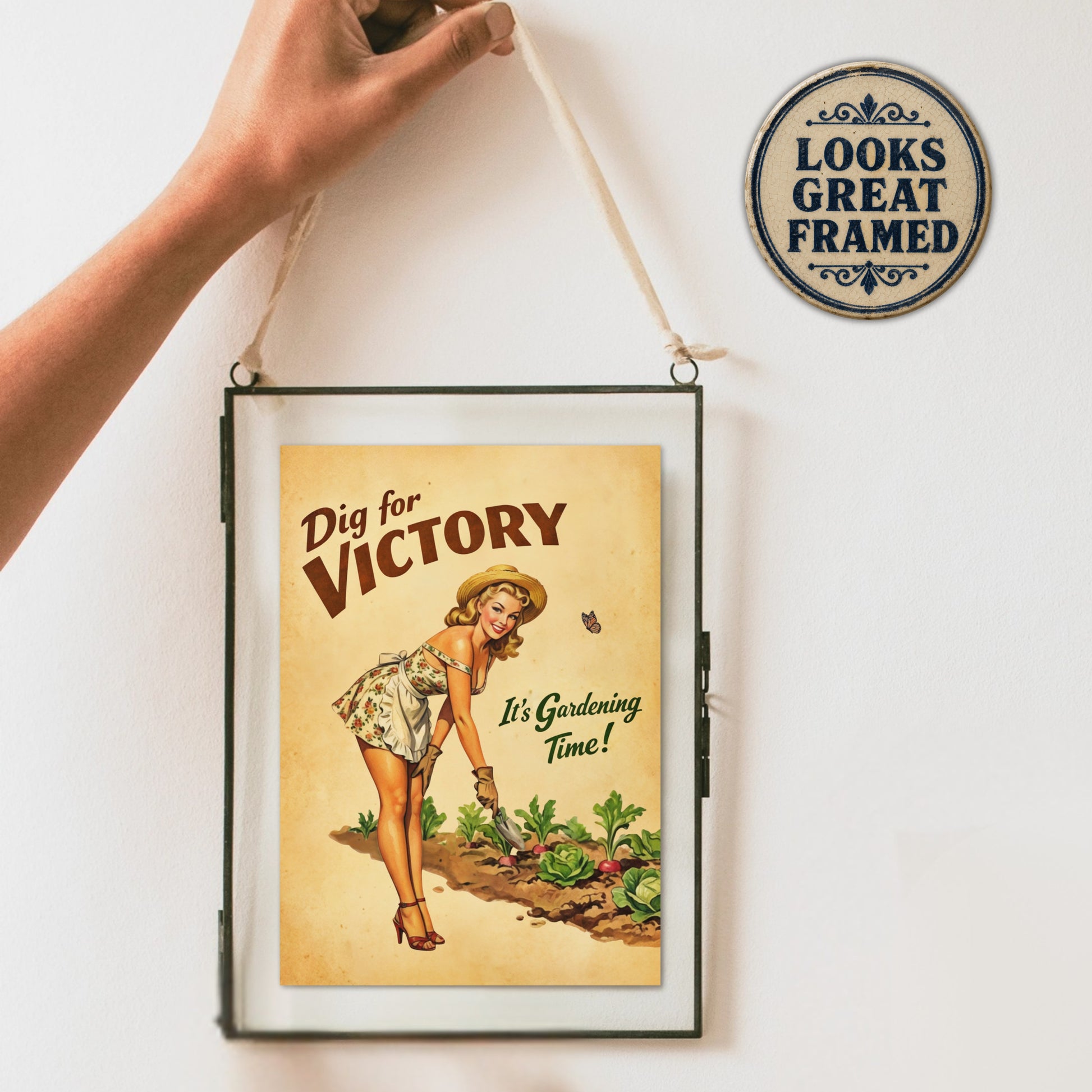 Framed 'Dig for Victory' poster with a person holding it against a white wall.