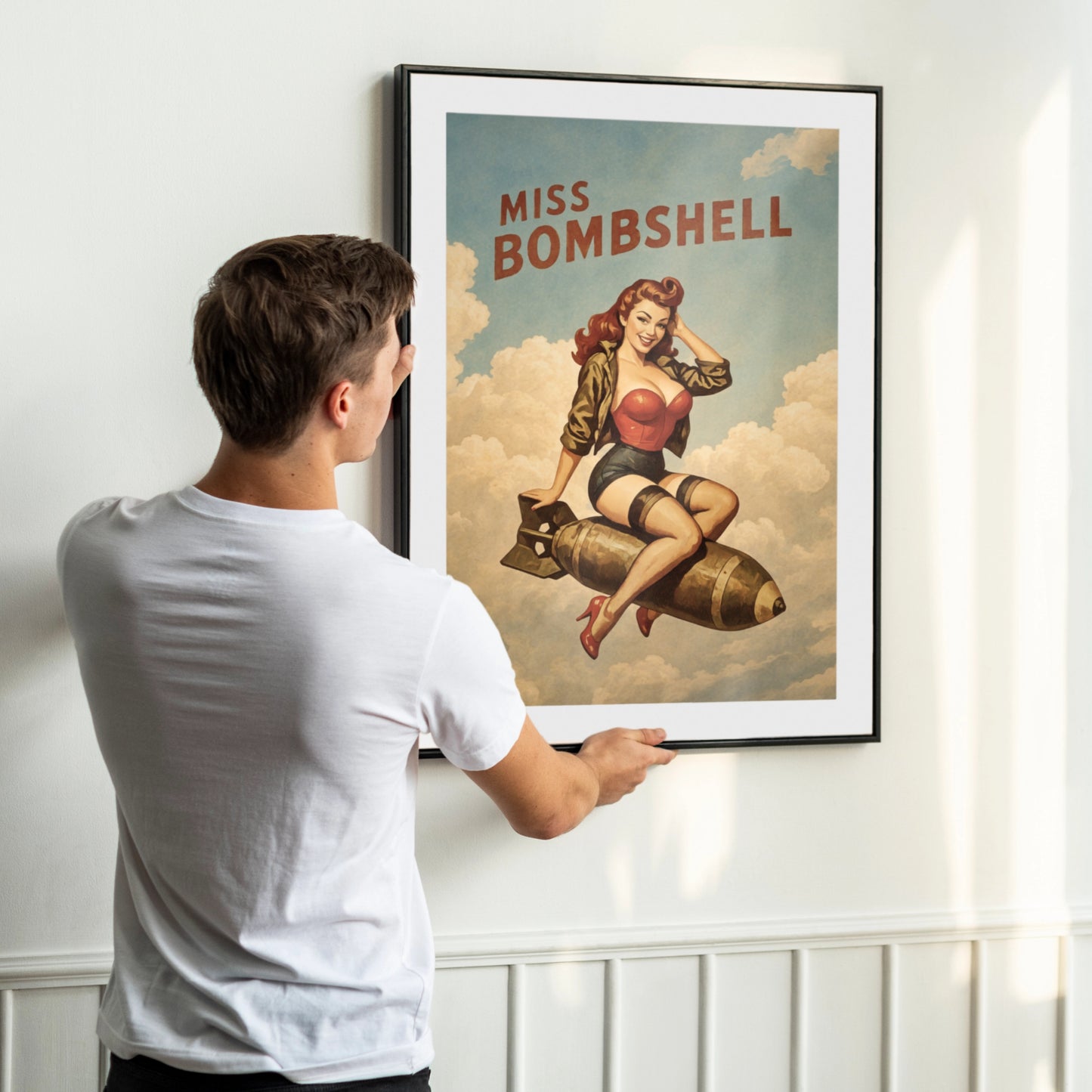Man hanging a framed poster of a woman on a bombshell design.