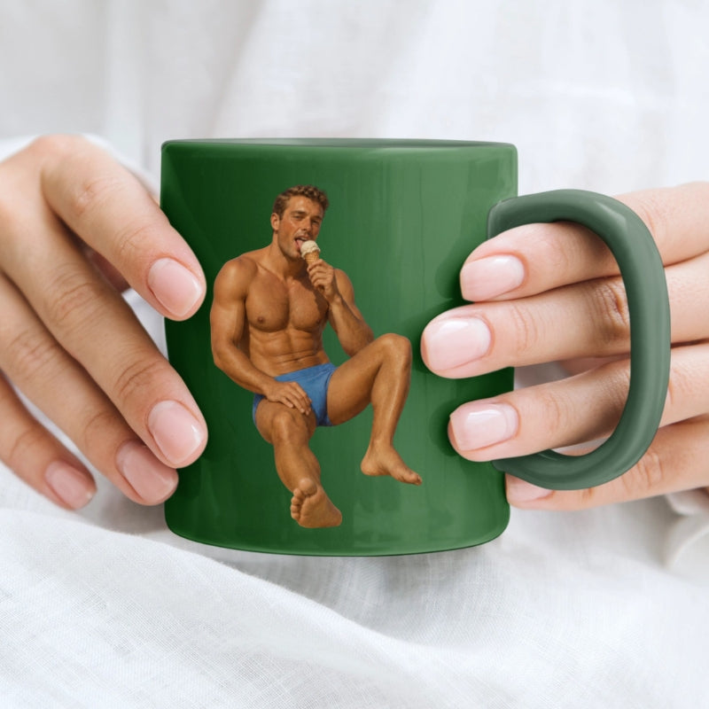 Green mug with a graphic of a shirtless man holding a banana, held by two hands.