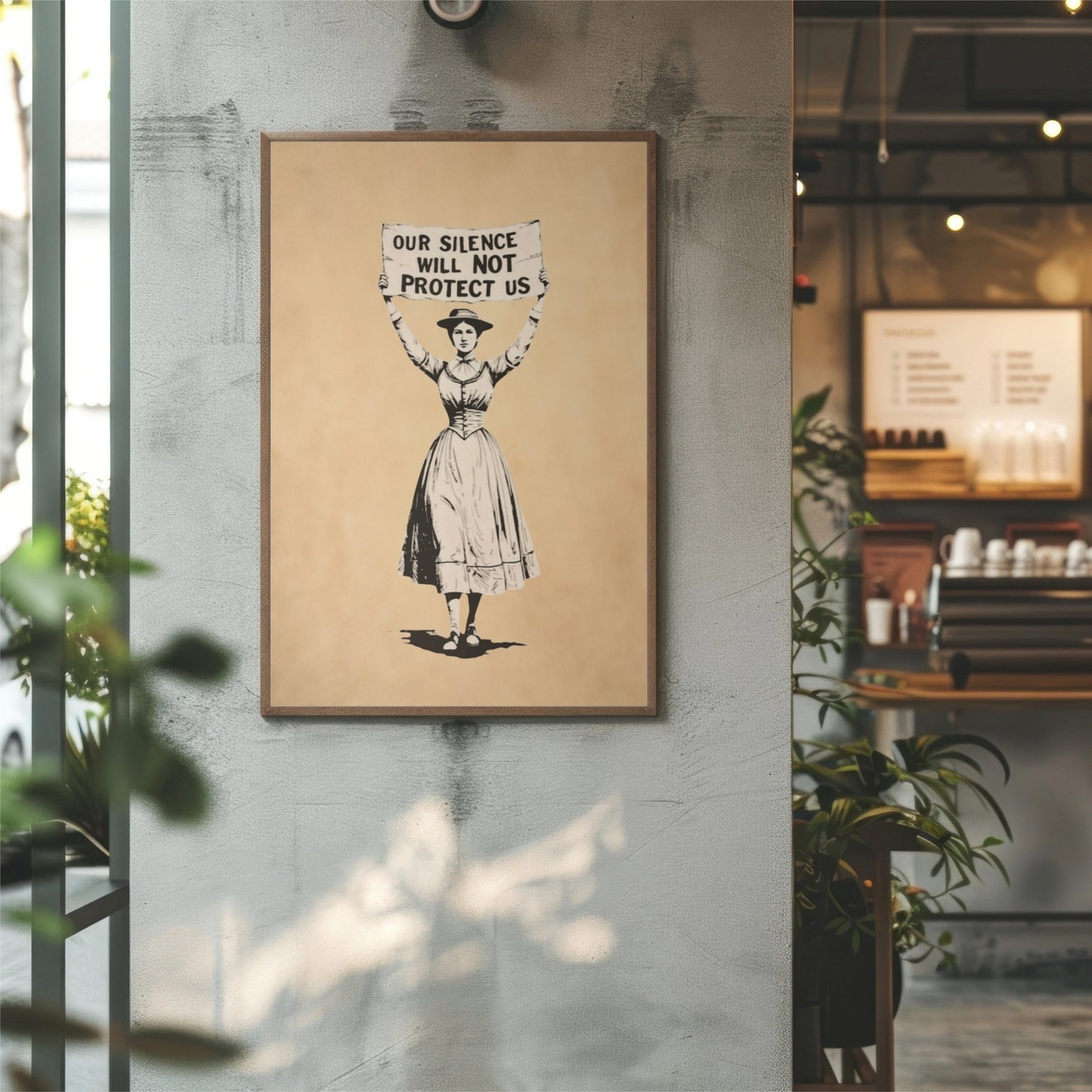 Framed artwork with a woman holding a Our Silence Will NOT Protect Us sign on a wall in an indoor setting.