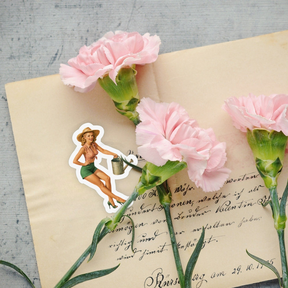 Pink carnations on an old letter with a vintage-style sticker of a woman holding a watering can.