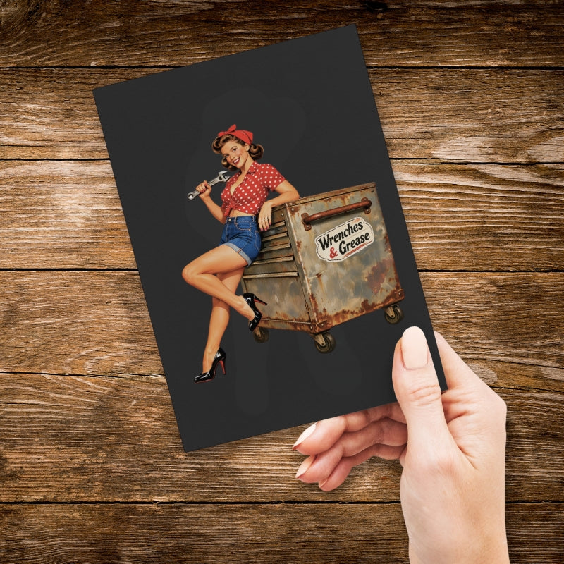 Notebook with a graphic of a woman holding a wrench on a toolbox, held by a hand on a wooden surface.