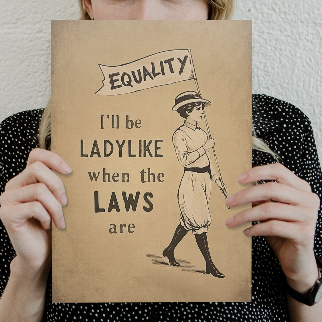 Person holding a sign with a vintage illustration of a woman holding an 'EQUALITY' banner and text.