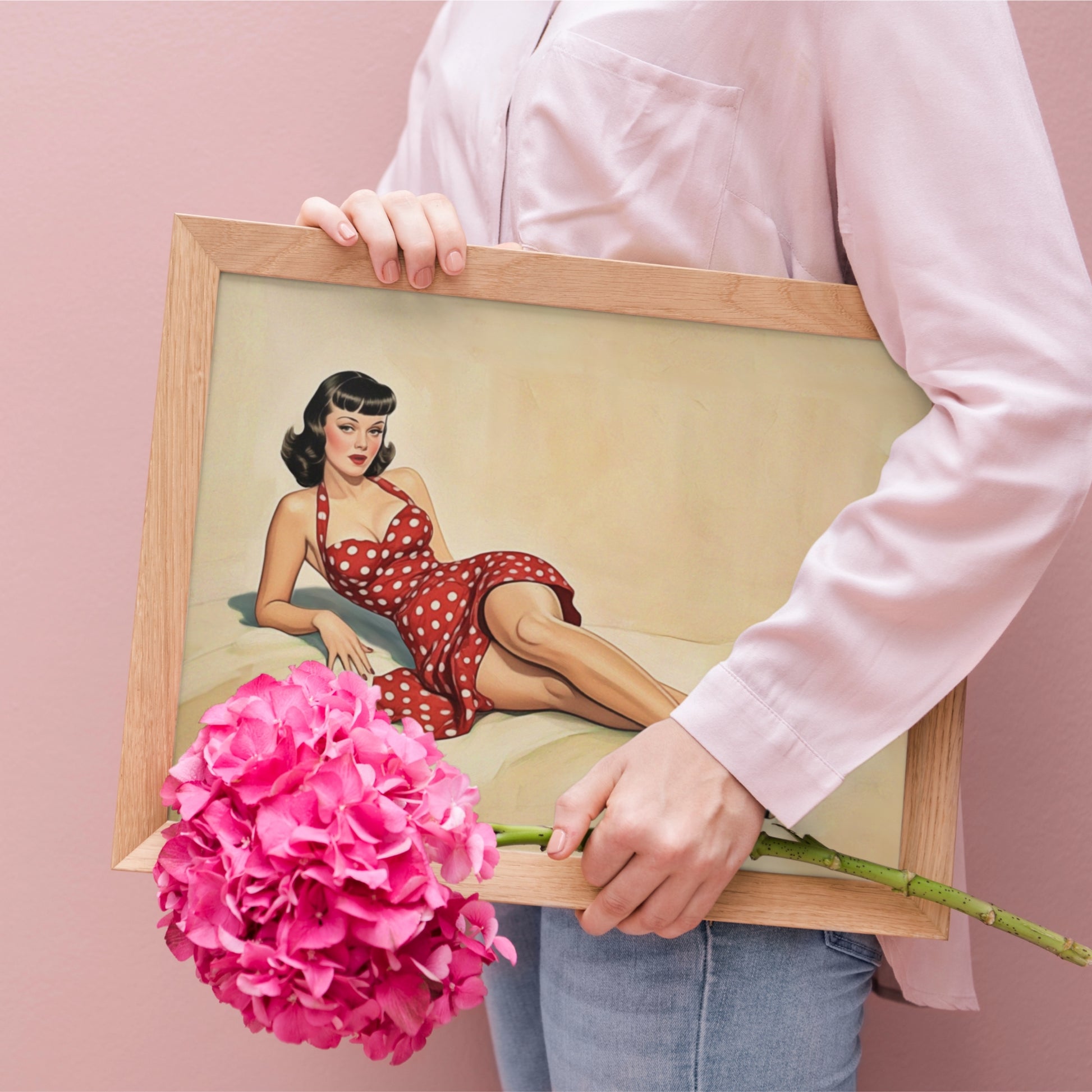 Person holding a framed pin-up-style illustration with a pink flower against a pink background