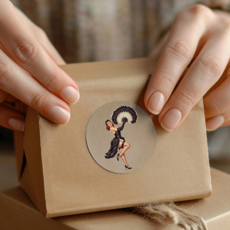 Brown paper package with a decorative sticker featuring a woman holding an umbrella, held by hands.
