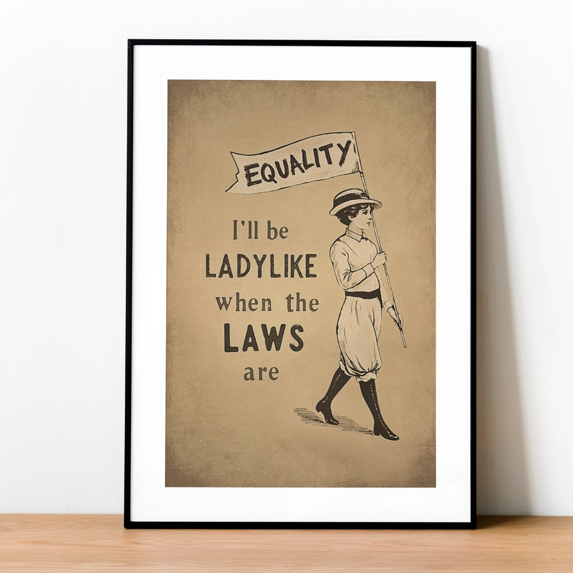 Framed poster with a woman holding a 'Equality' banner on a brown background.