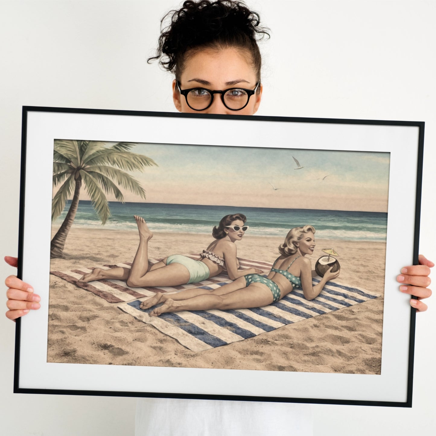 Person holding a framed picture of women on a beach
