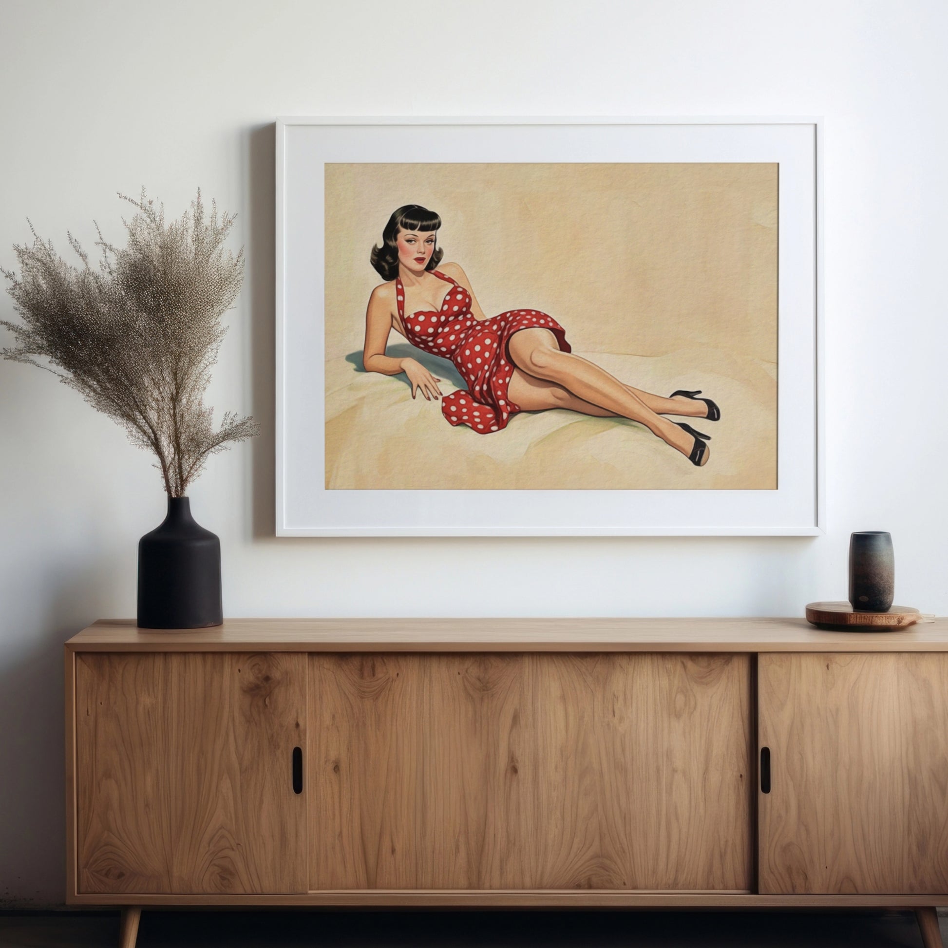 Framed artwork of a woman in a red polka dot dress on a wall above a wooden cabinet.