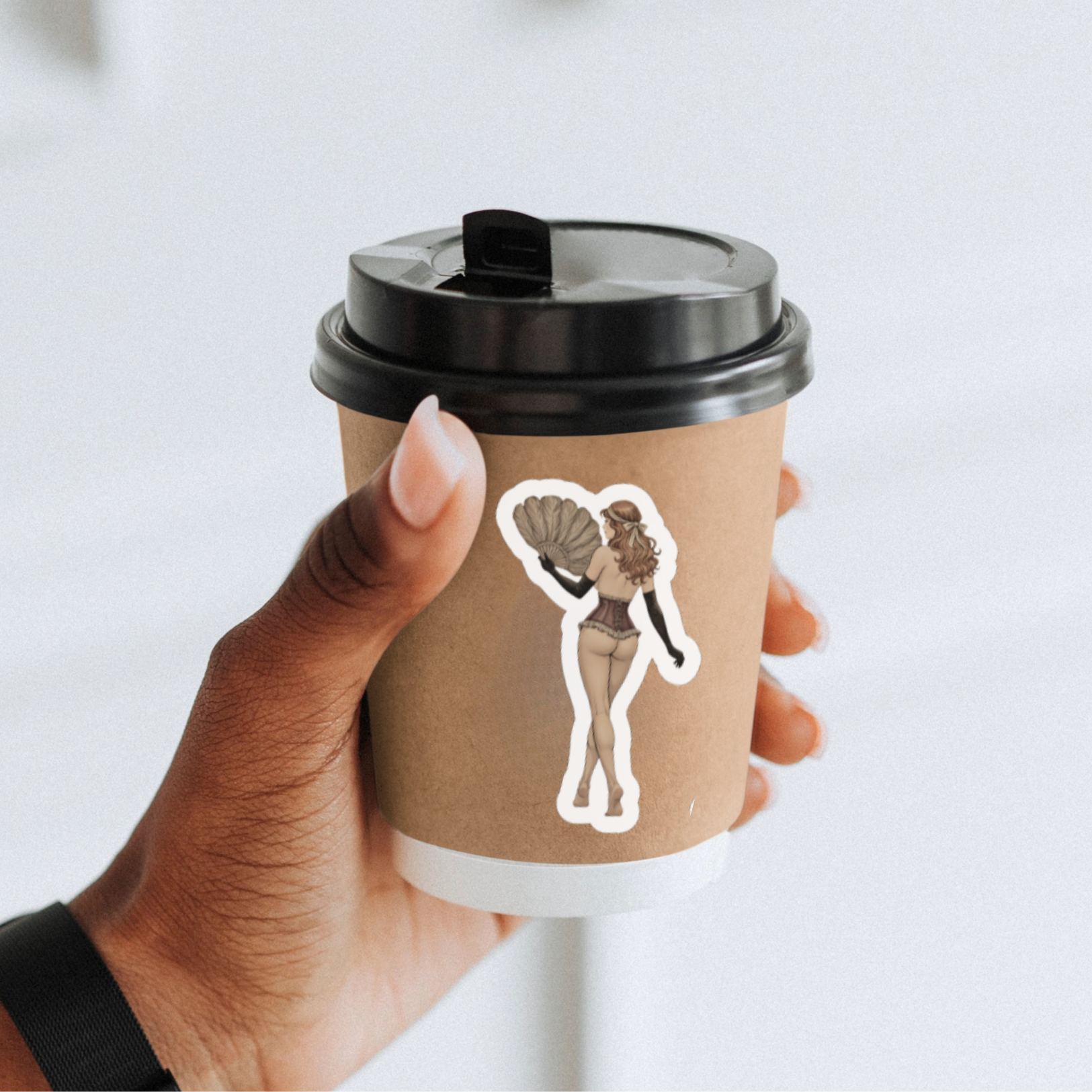 Hand holding a coffee cup with a sticker of a woman holding a fan on a white background