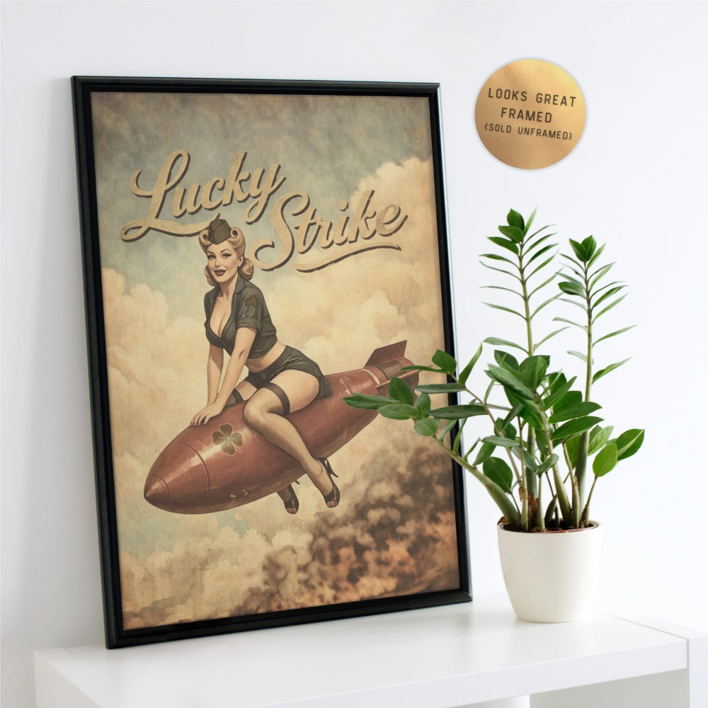 Framed Lucky Strike poster with a woman on a rocket, placed on a white surface with a plant.