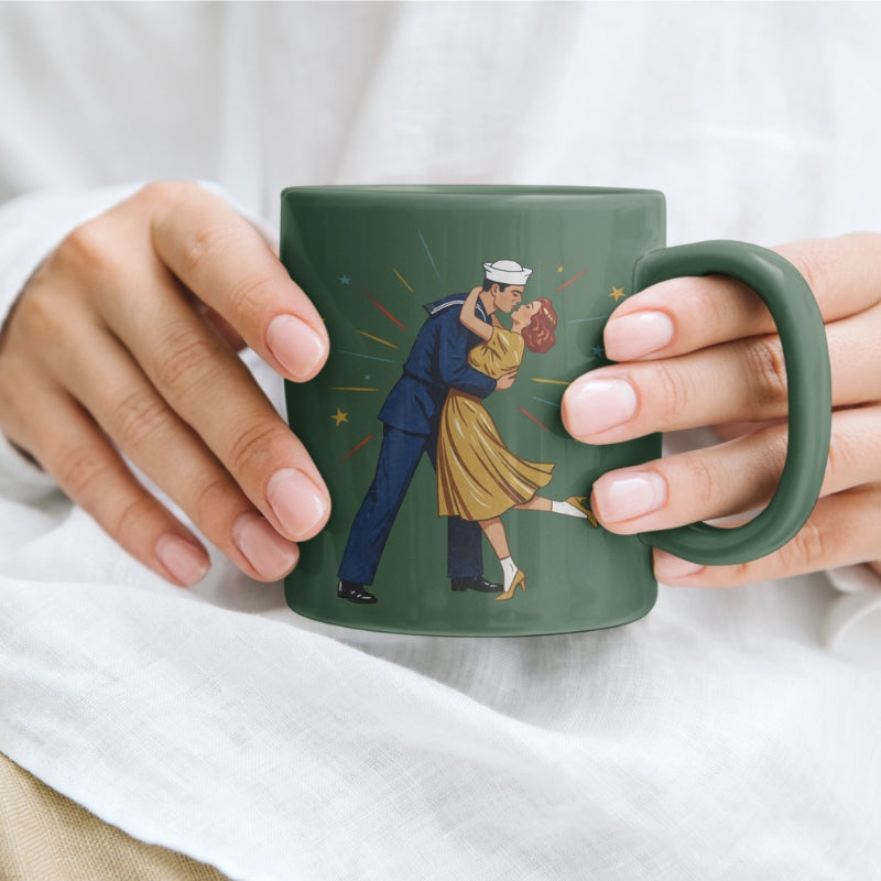 Green mug with a design of a sailor and dancer being held by hands against a white background