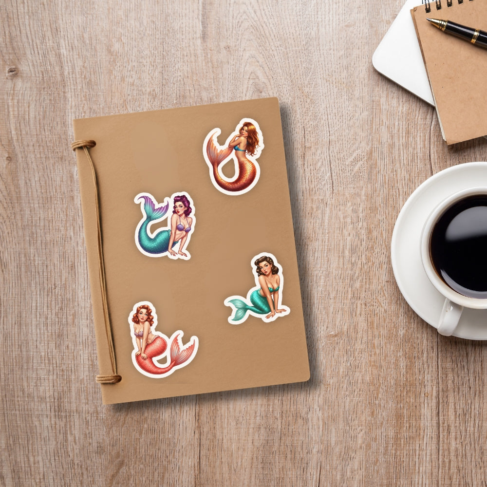 Notebook with mermaid stickers on a wooden surface next to a cup of coffee.