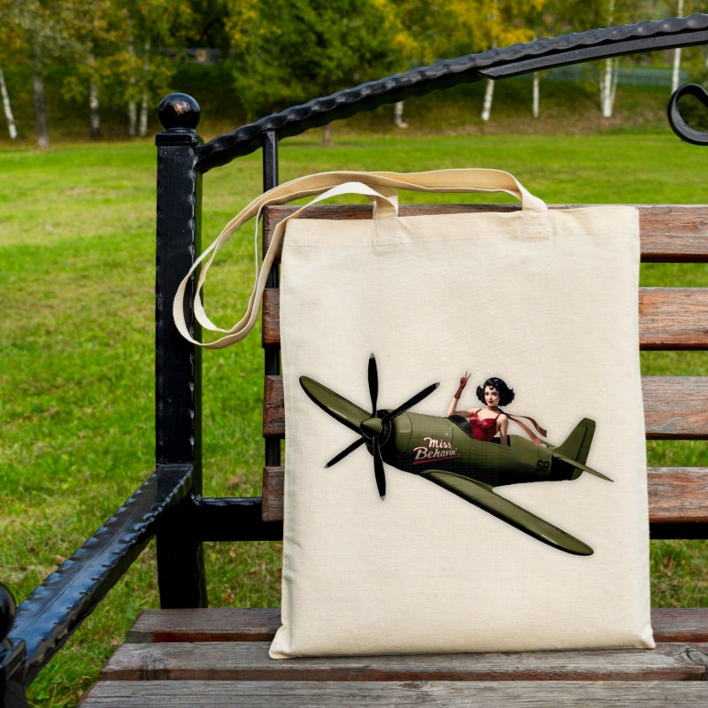 Tote bag with airplane and woman design on a wooden bench outdoors