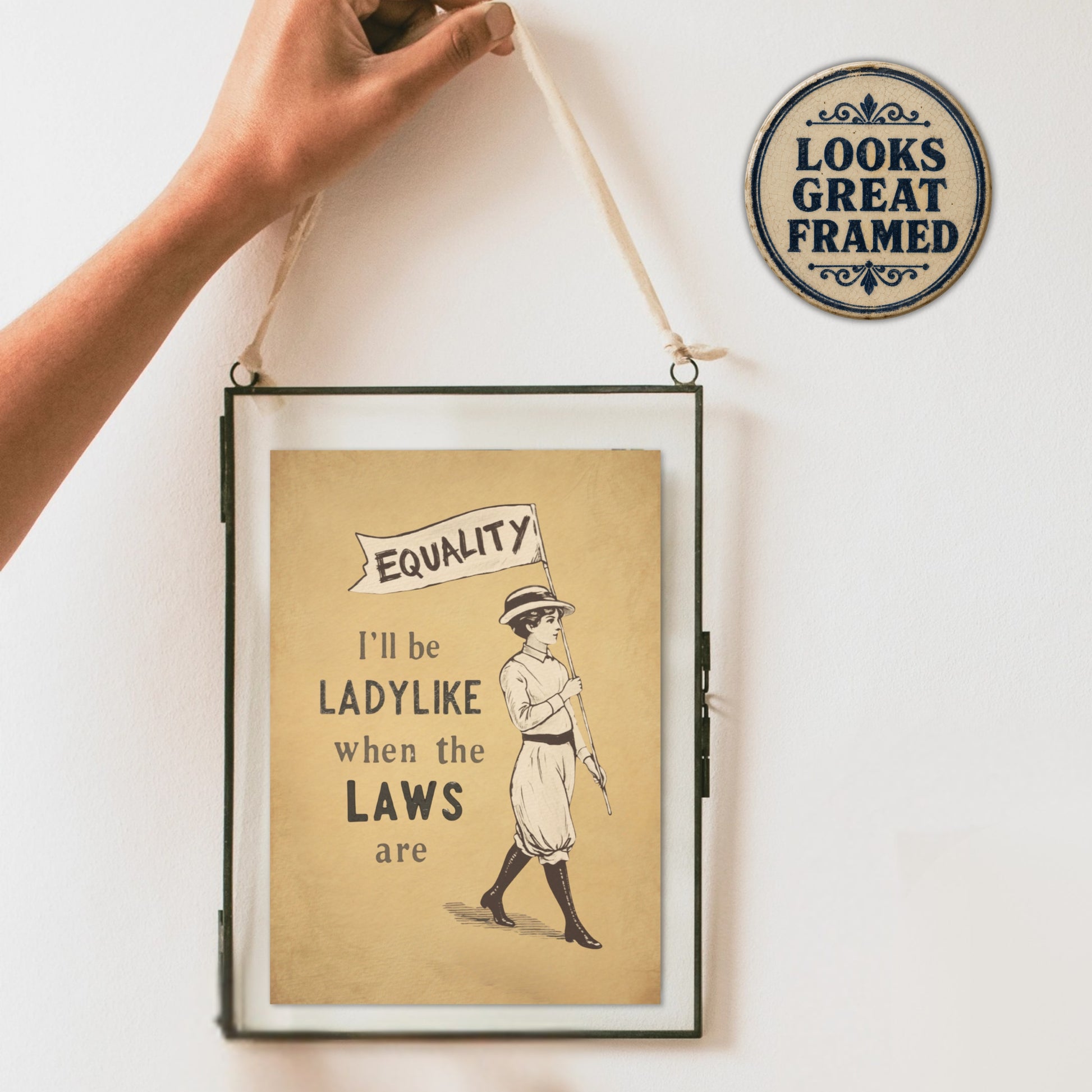 Framed feminism poster with a vintage-style illustration and text on a white wall.