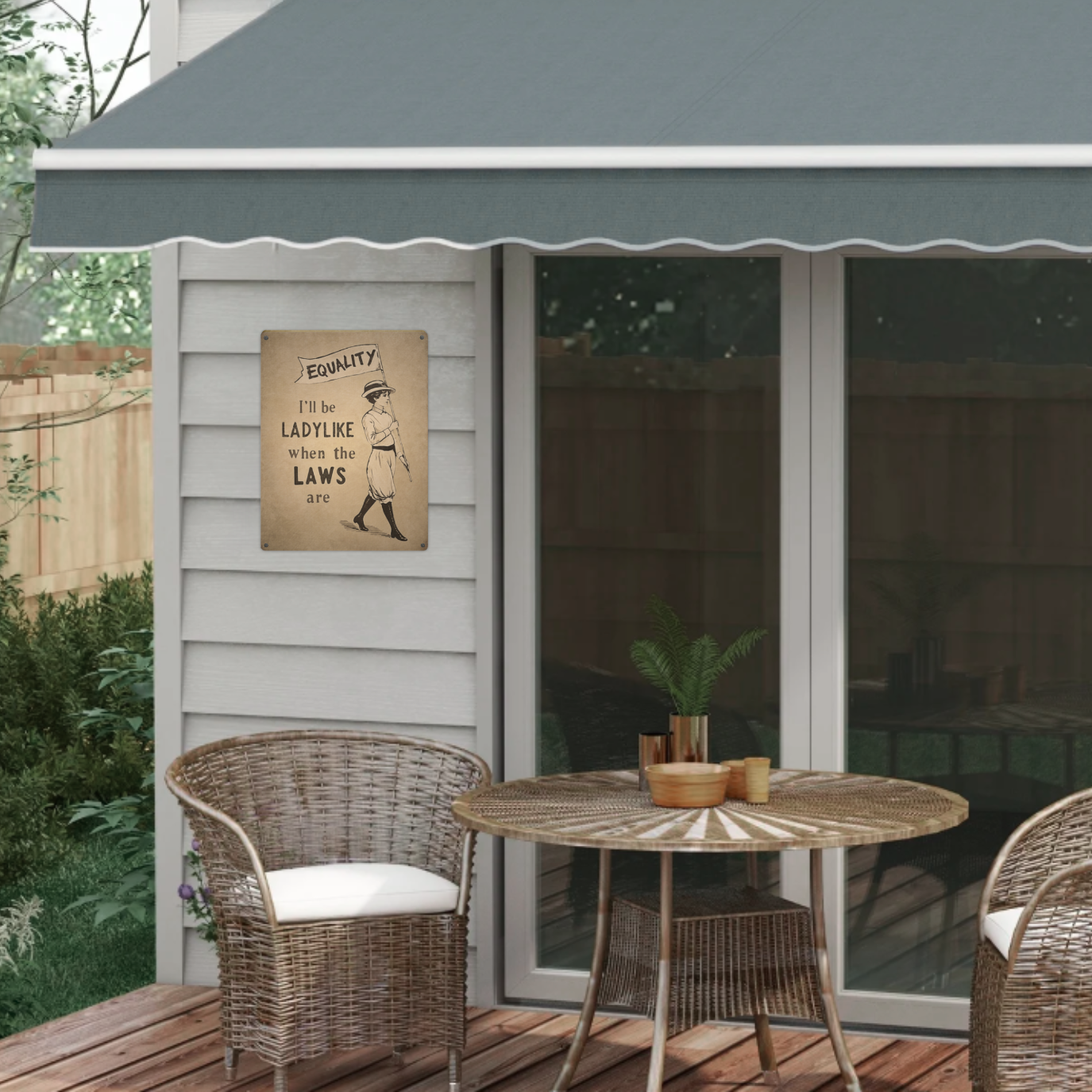 Outdoor patio with wicker furniture, table, and decorative woman's rights sign on a wall