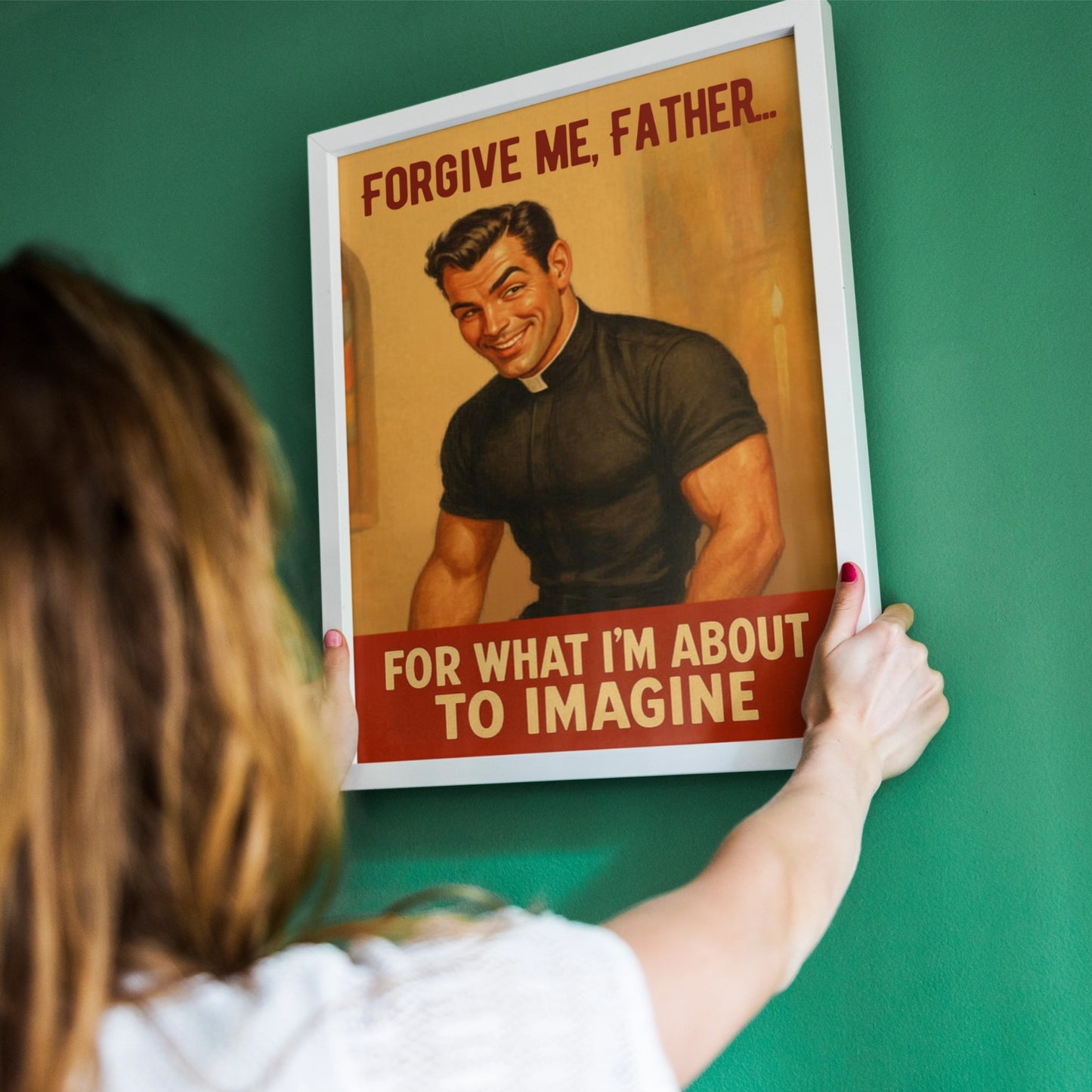 Person holding a framed poster with a humorous religious-themed illustration on a green wall.