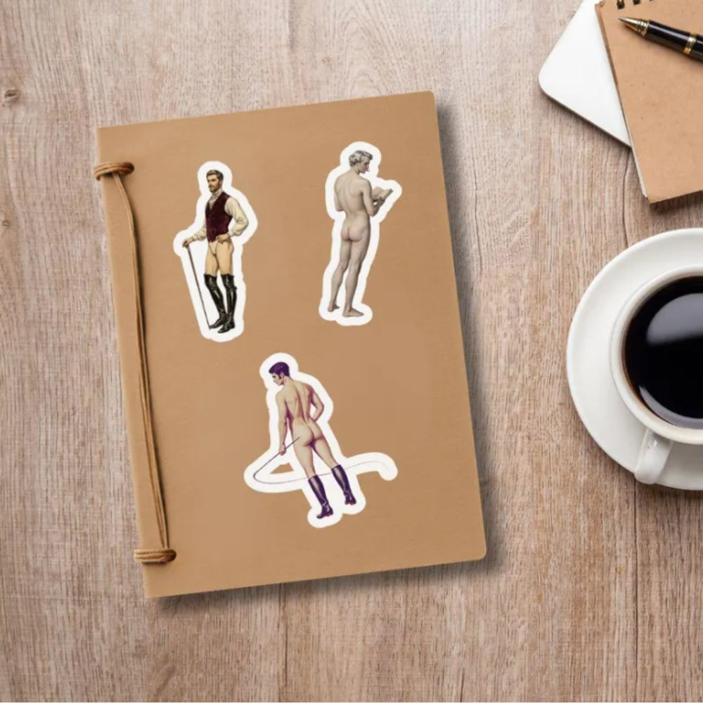 Notebook with stickers of men in various poses on a wooden surface with a coffee cup.